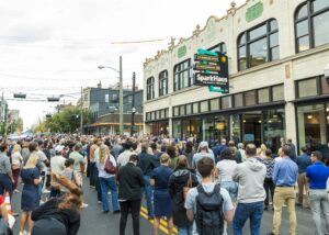 Exterior of SparkHaus at grand opening with people standing on Madison Avenue